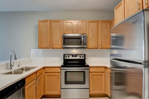 an empty kitchen with wooden cabinets and stainless steel appliances