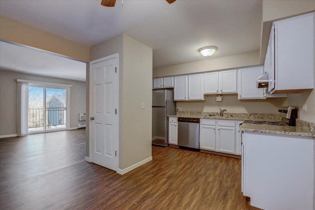 an empty kitchen with white cabinets and a door to a balcony