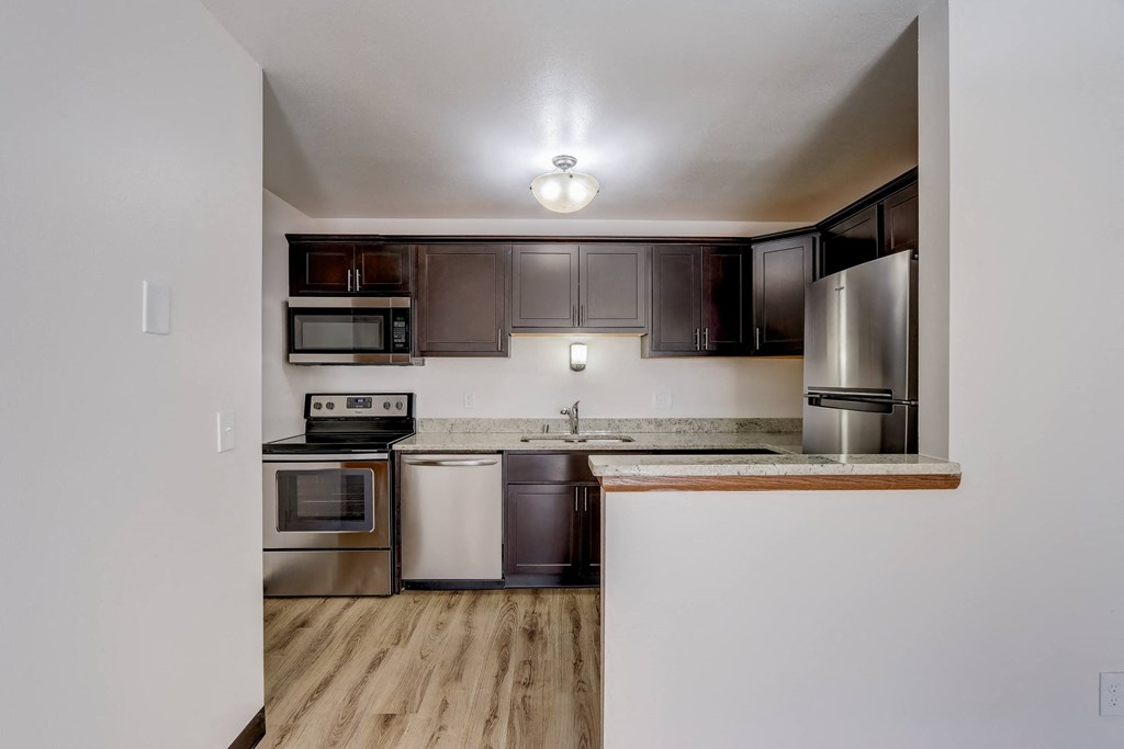 a kitchen with dark wood cabinets and stainless steel appliances