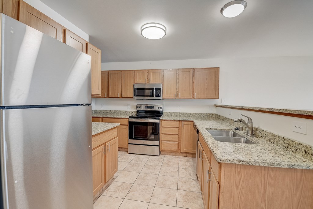 an empty kitchen with wooden cabinets and granite counter tops