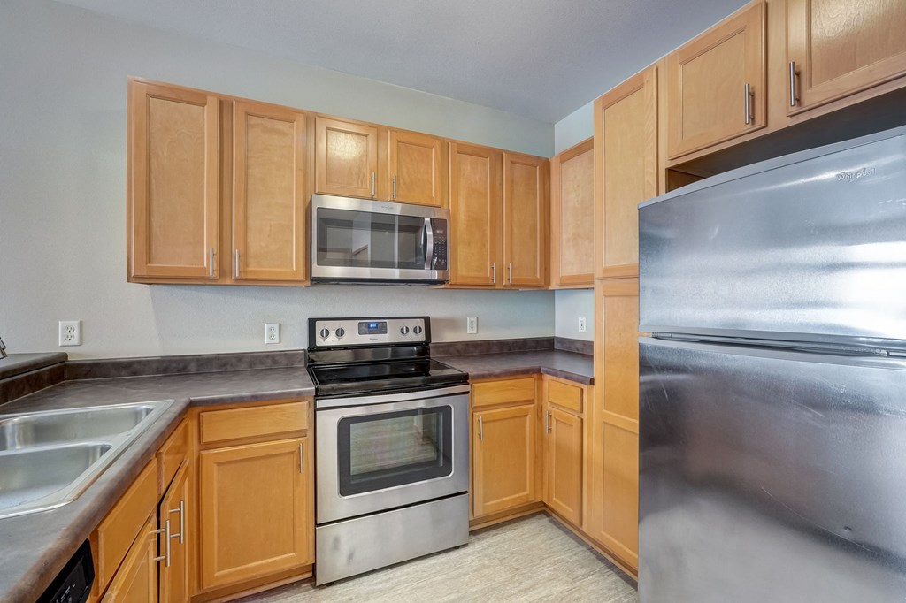an empty kitchen with stainless steel appliances and wooden cabinets