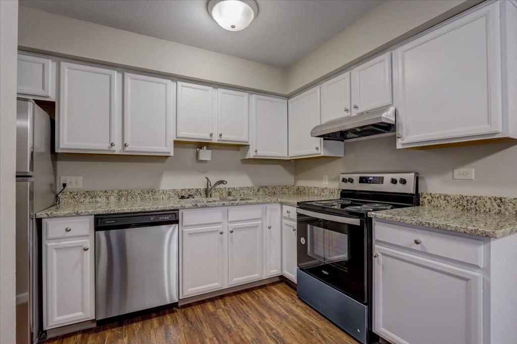 a kitchen with white cabinets and granite counter tops