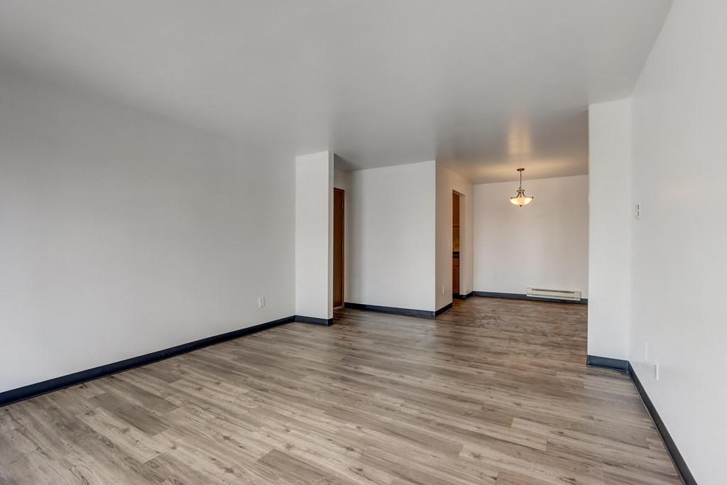an empty living room with hardwood floors and white walls