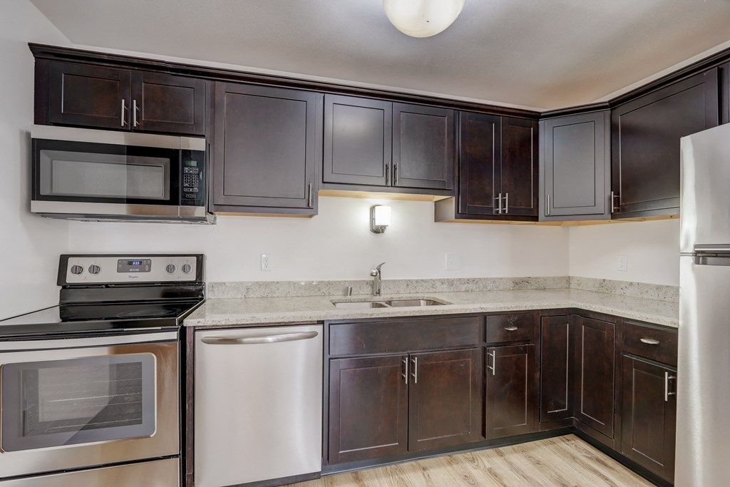 a kitchen with dark wood cabinets and stainless steel appliances