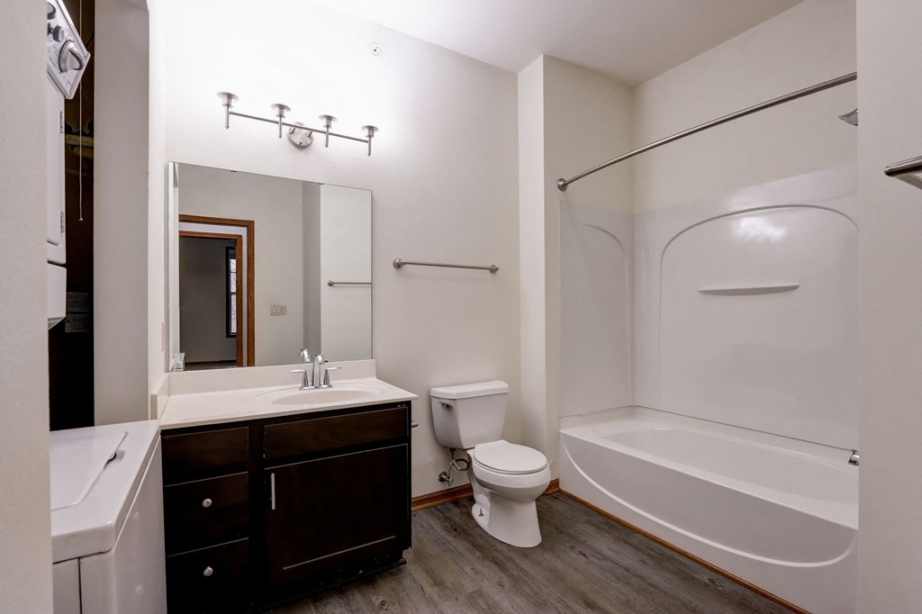 a bathroom with a tub sink and toilet and a mirror