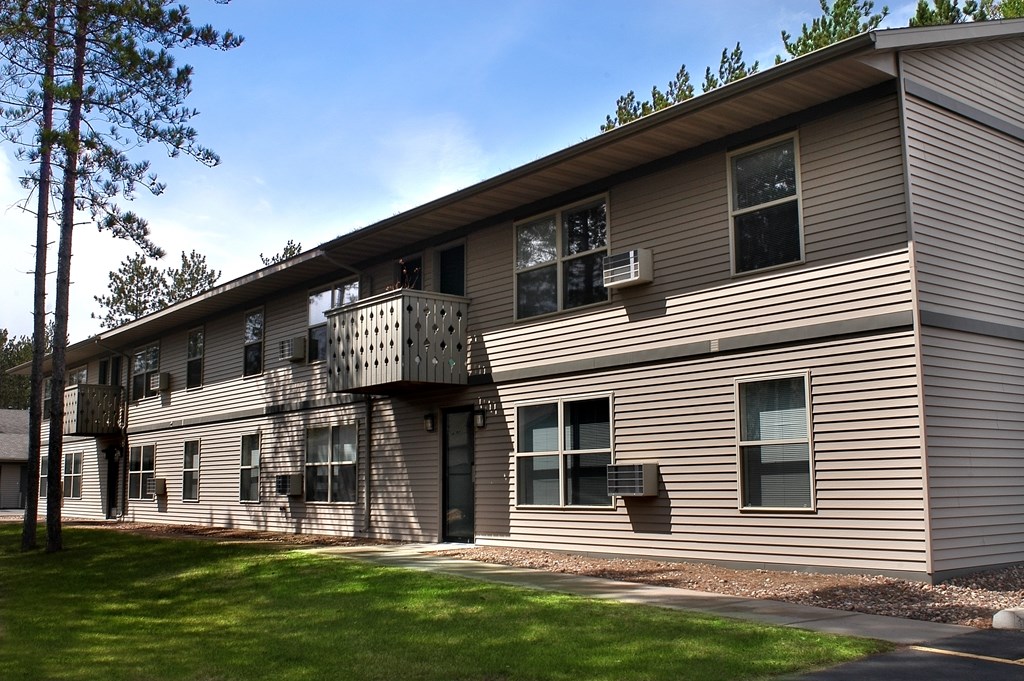A building with a balcony and a green lawn in front.