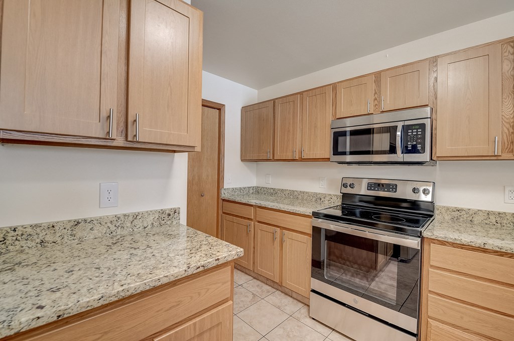 a kitchen with wooden cabinets and granite counter tops and a stove and microwave