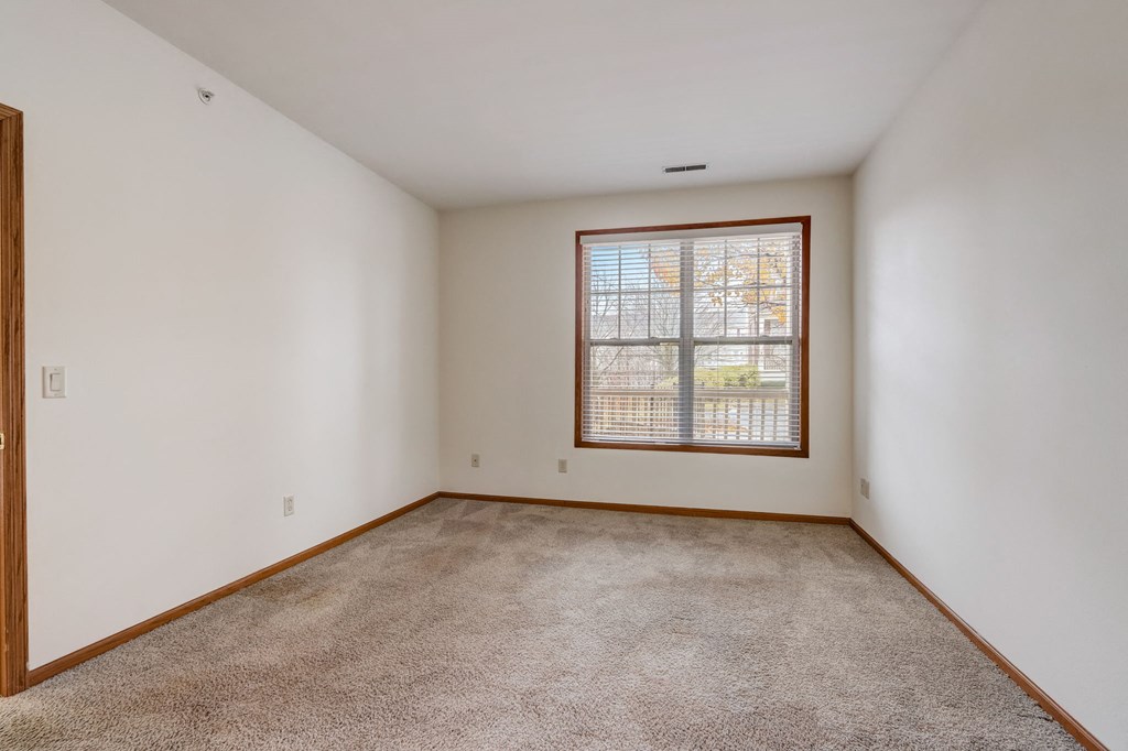 an empty living room with a window and carpet