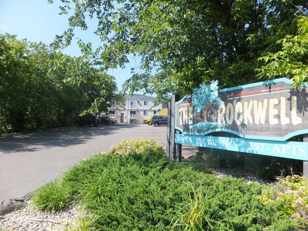 a sign for the rockwell apartments in front of a parking lot
