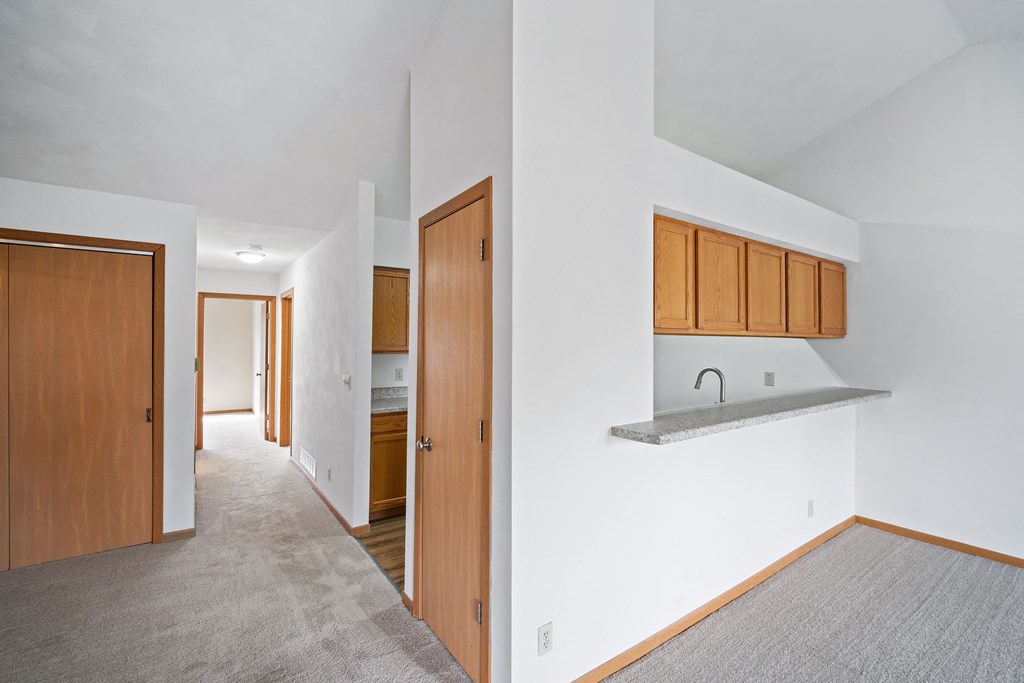 a living room with a kitchen and a door to a hallway