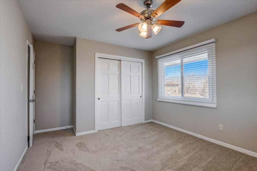 a bedroom with a ceiling fan and a window