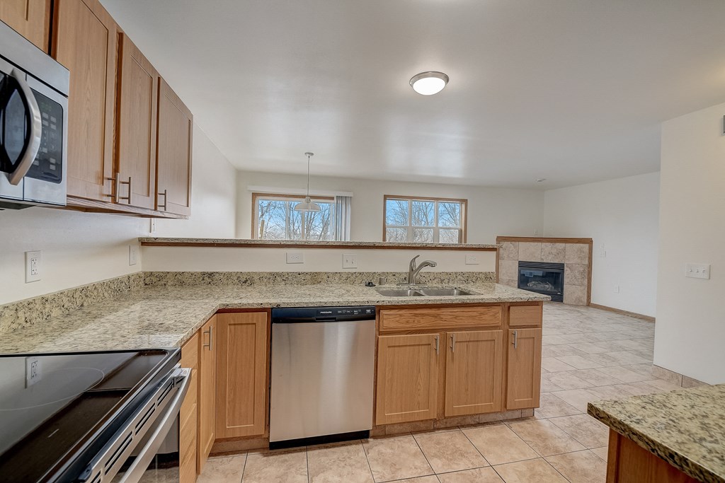 an empty kitchen with granite counter tops and a stove and dishwasher