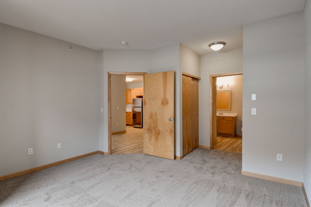 an empty living room with a door to a bedroom and a bathroom