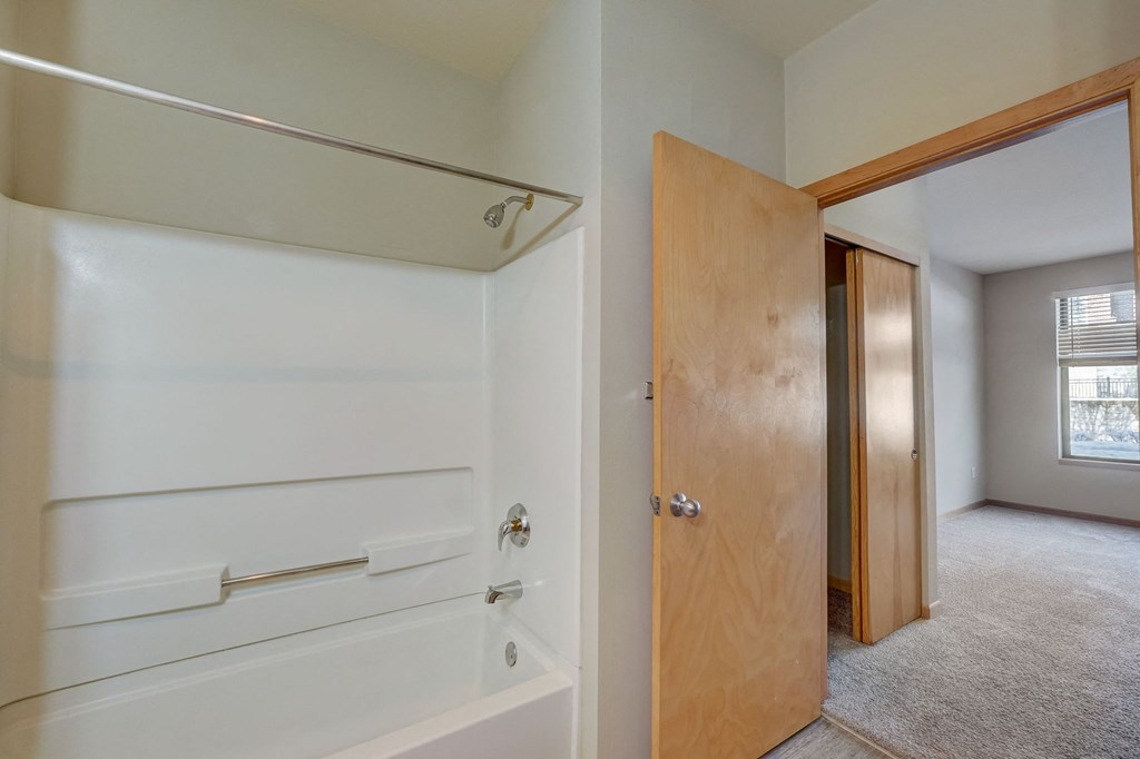 the door to the bathroom is open to the hallway and the bedroom is empty