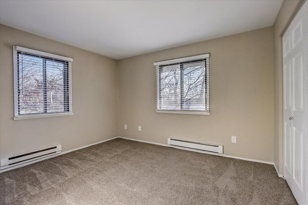 an empty living room with two windows and carpet