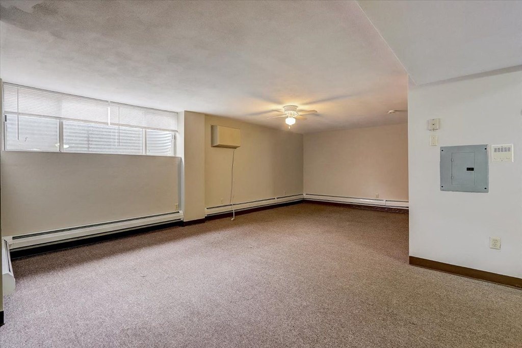 an empty living room with a large window and a ceiling fan