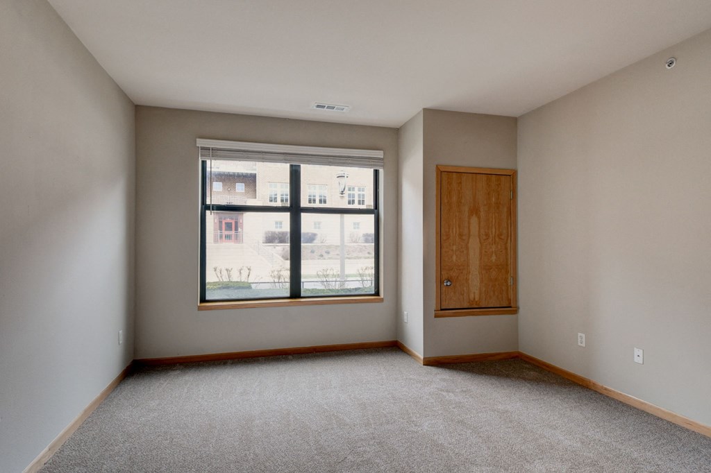 an empty living room with a large window and a wooden door