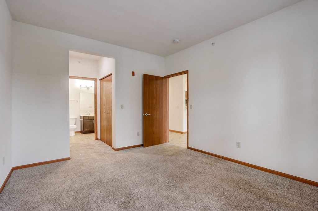 a living room with carpet and a door to a bathroom