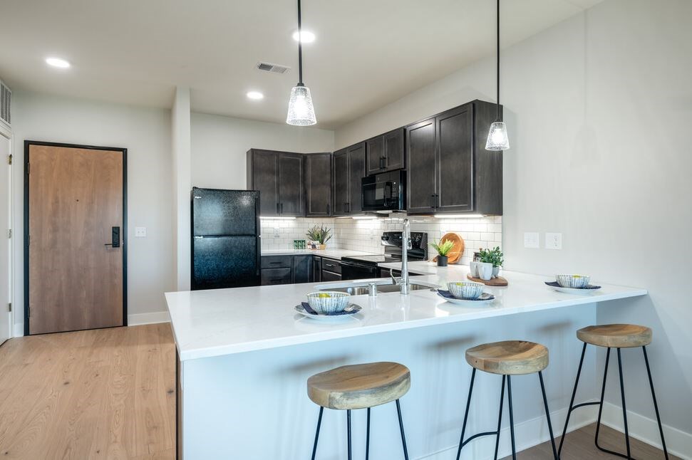 A kitchen with a white countertop and black cabinets.
