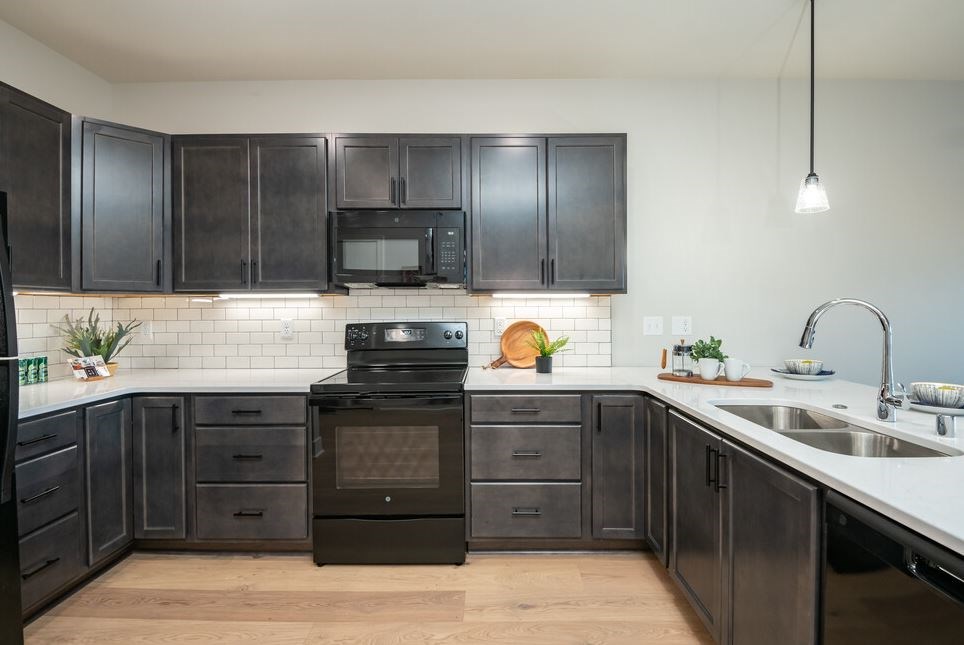 A kitchen with black cabinets and a black oven.
