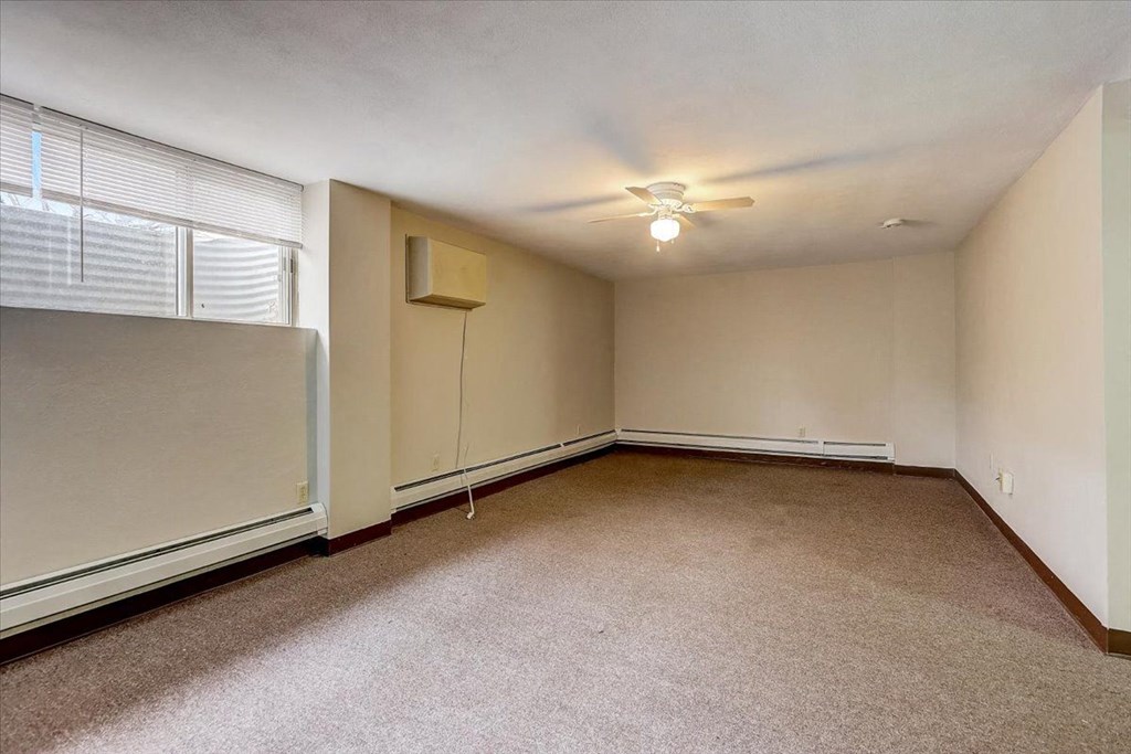 an empty living room with a ceiling fan and a window