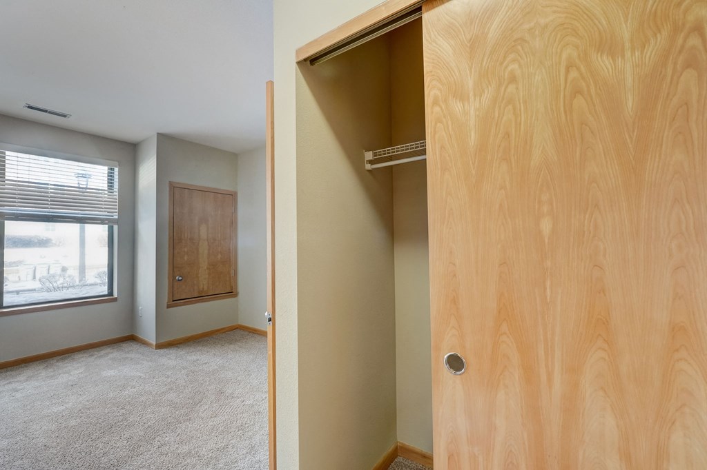 an empty bedroom with a closet and a window
