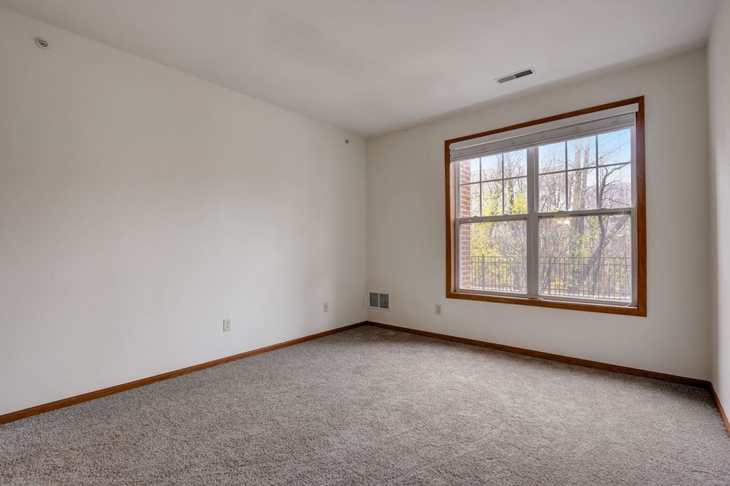an empty living room with a large window and carpet