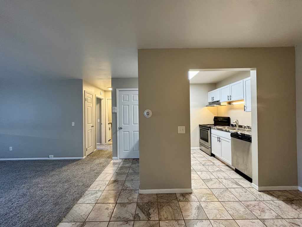 A kitchen with a white door and a tiled floor.