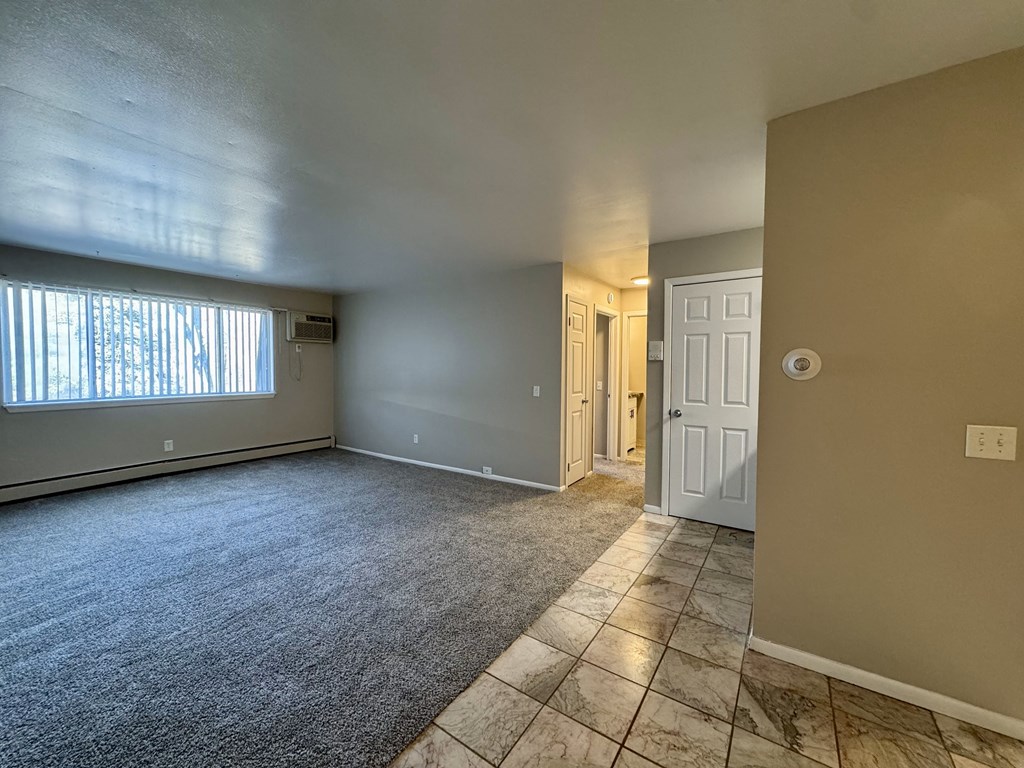 A room with a carpeted floor and a door on the right side.