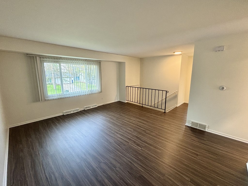 A room with wooden flooring and a window with blinds.