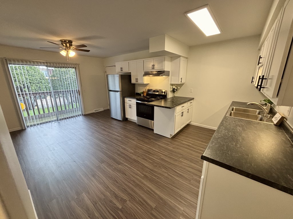 A kitchen with white cabinets and a black countertop.