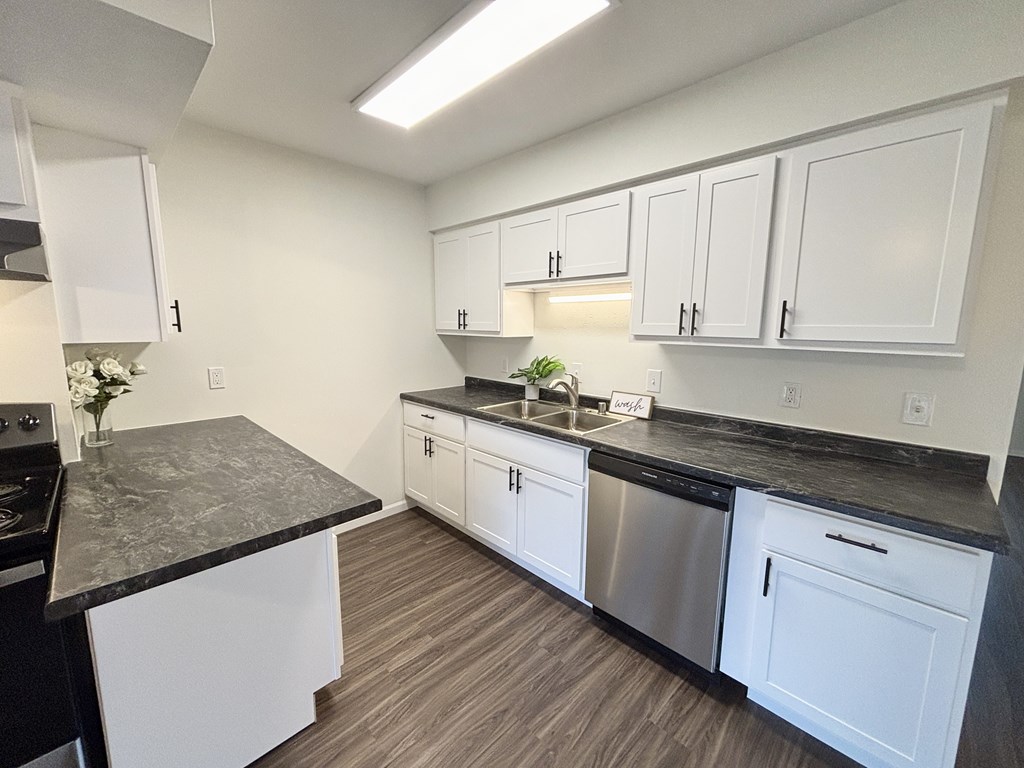 A kitchen with white cabinets and a black countertop.