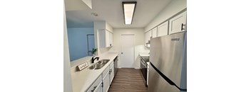 A kitchen with a stainless steel refrigerator and a sink with a sign that says "wash" on it.