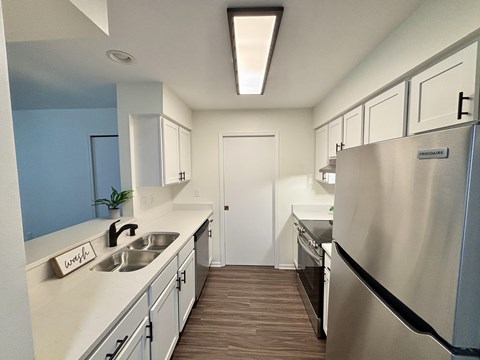 A kitchen with a stainless steel refrigerator and a sink with a sign that says "wash" on it.