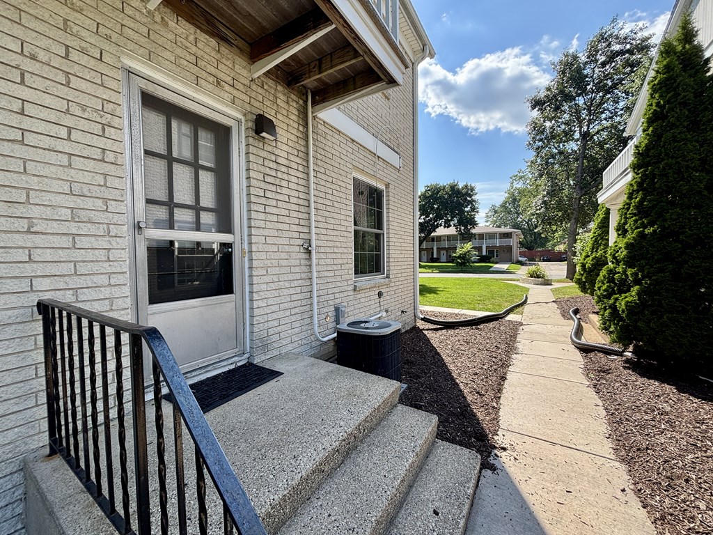 A house with a white door and a black railing on the steps.