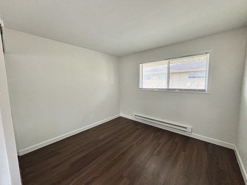 A room with a window and a radiator on the floor.