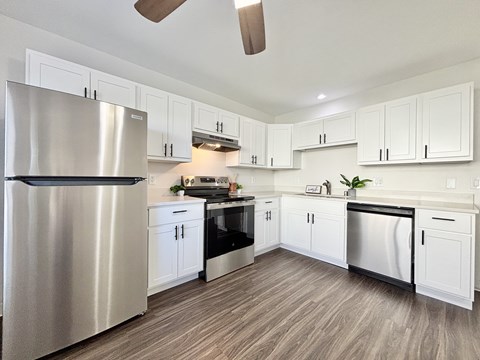 A modern kitchen with a stainless steel refrigerator and wooden flooring.