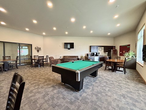 A room with a pool table and chairs.