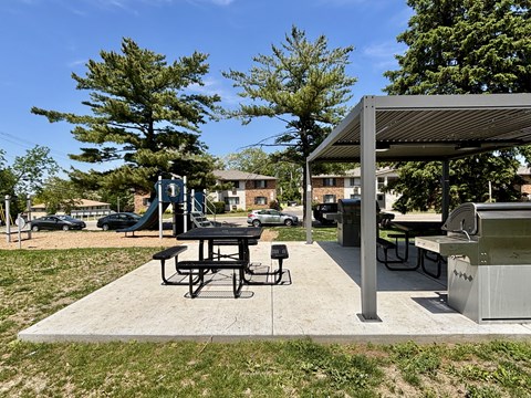 A picnic area with a table and chairs under a shelter.