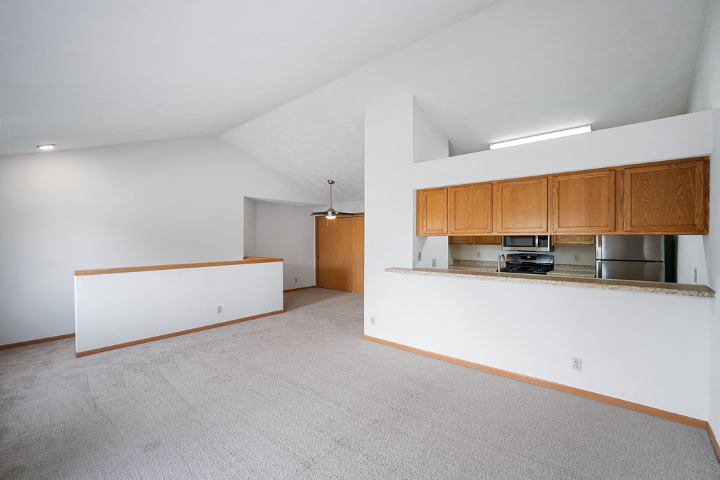 a kitchen and living room with white walls and wood cabinets