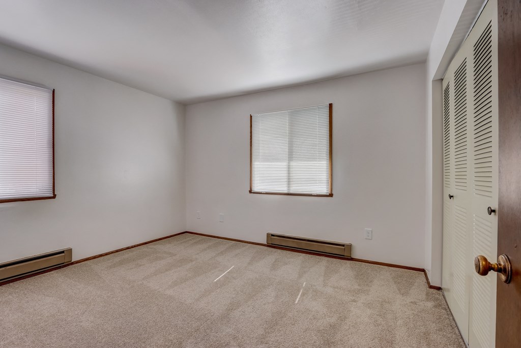 a bedroom with two windows and a door