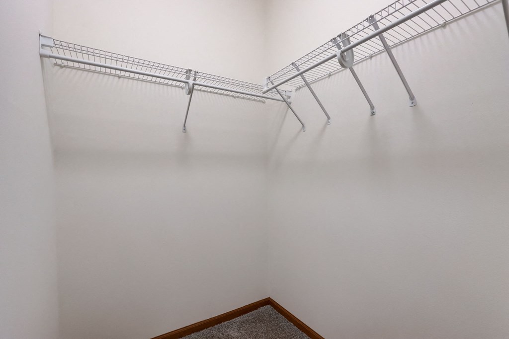 an empty closet with three metal shelves on the wall
