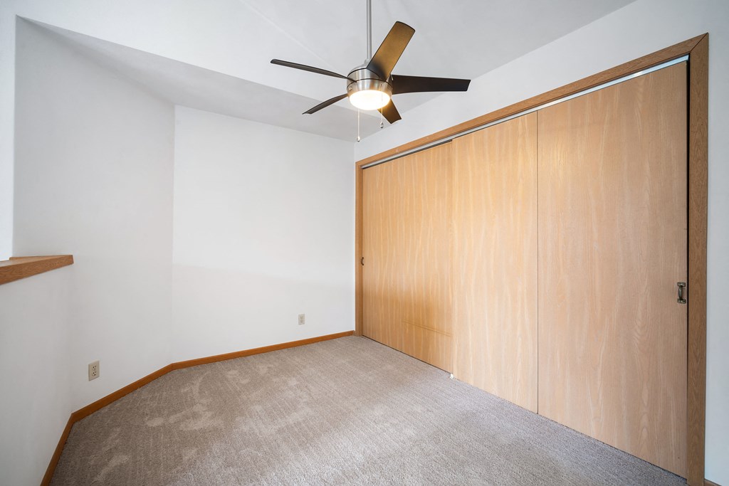 an empty room with a ceiling fan and a closet