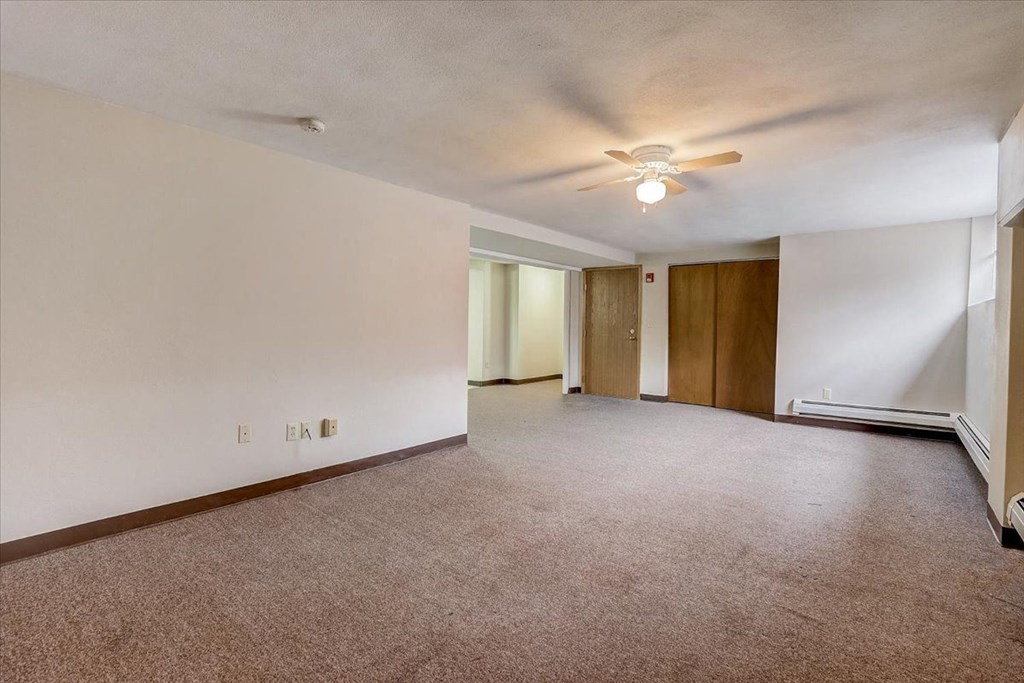 an empty living room with white walls and a ceiling fan