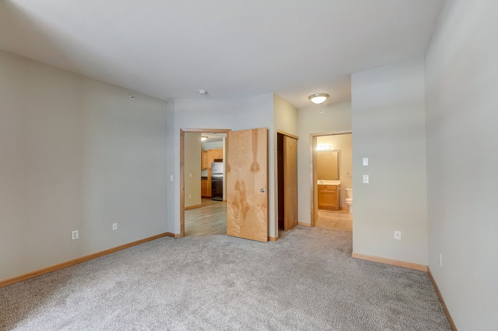 a living room with carpet and a door into a bedroom