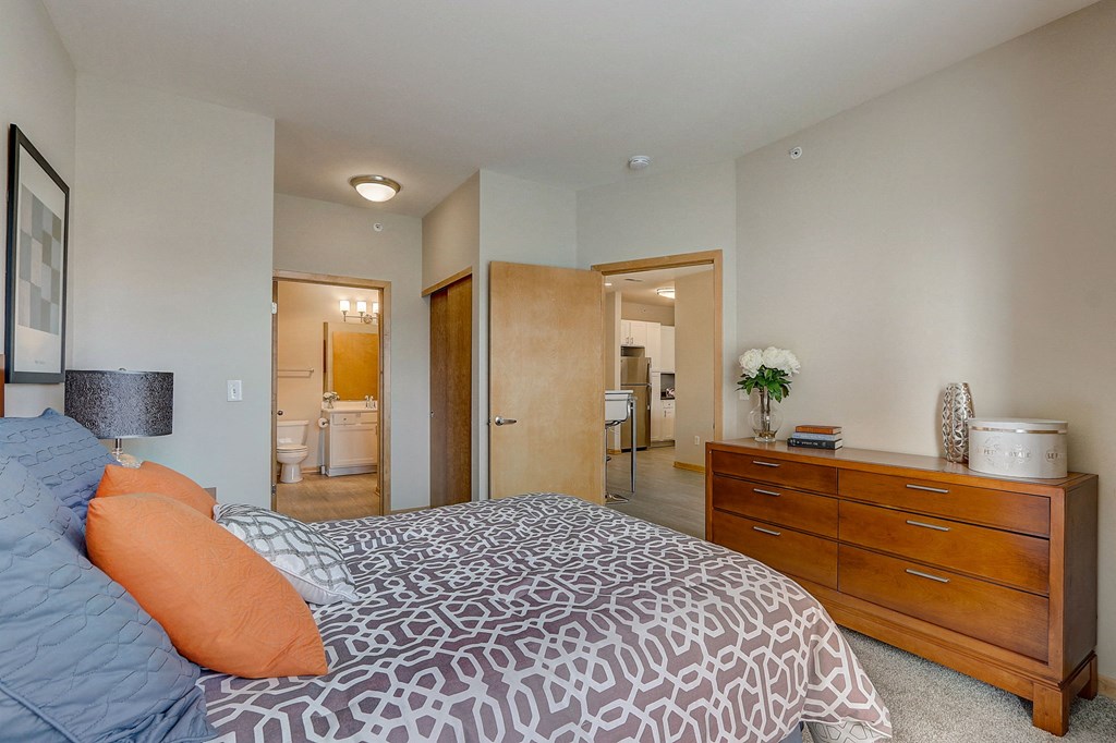 a bedroom with a bed and a dresser and a bathroom