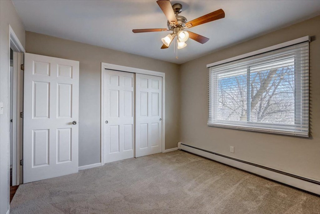 an empty living room with a ceiling fan and a window