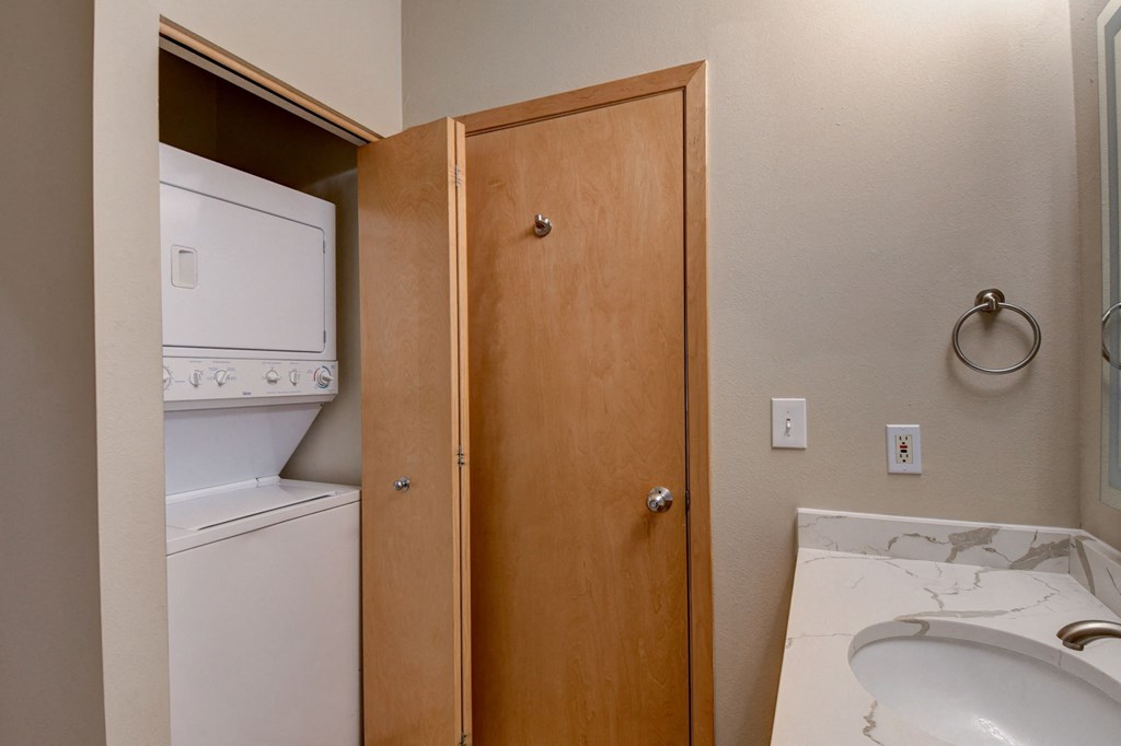 a bathroom with a washer and dryer and a sink and a door to
