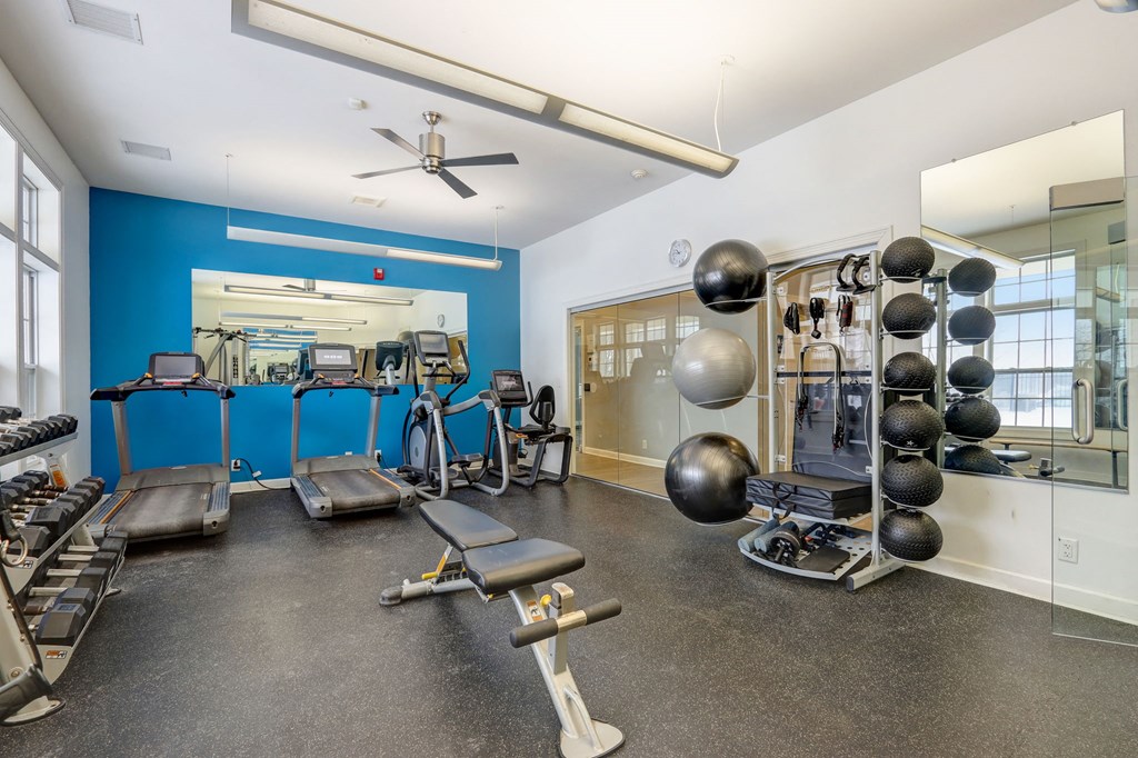 a gym with weights and cardio equipment and a window