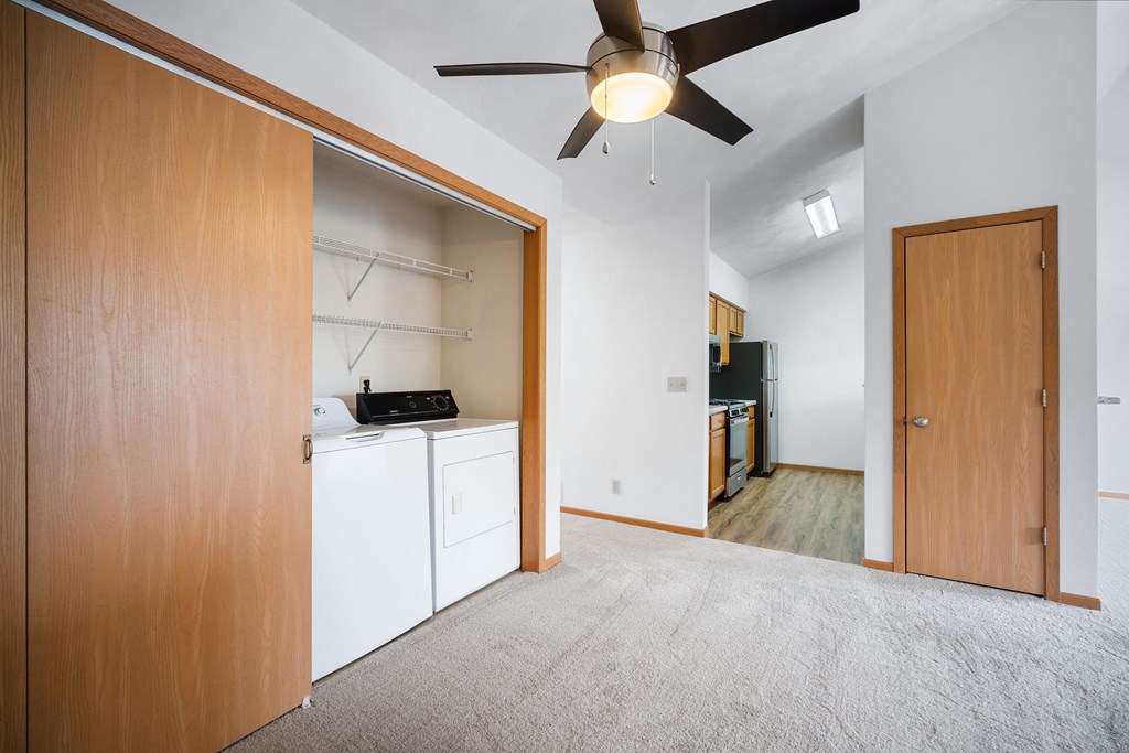an empty room with a kitchen and a ceiling fan